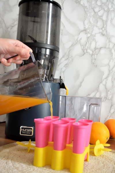 Mettere succo nelle forme dei ghiaccioli Il succo per la ricetta ghiaccioli all'arancia